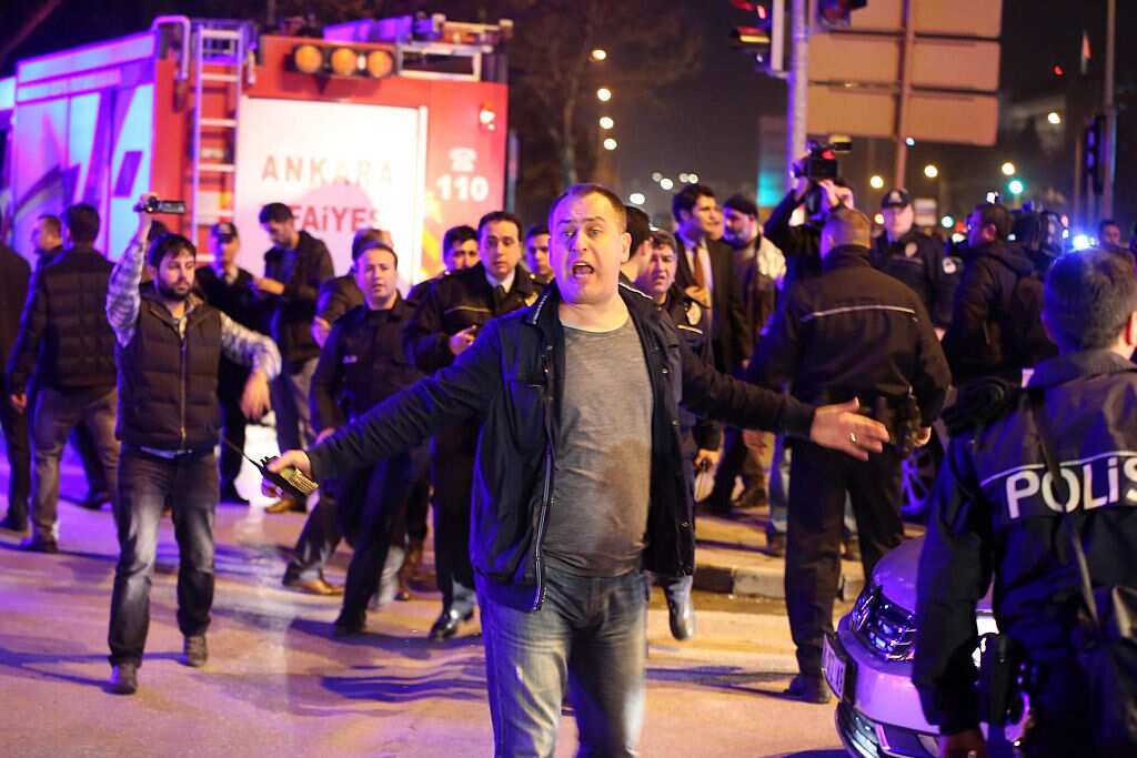 A man reacts next to policemen near the site of an explosion after an attack targeted a convoy of military service vehicles in Ankara.