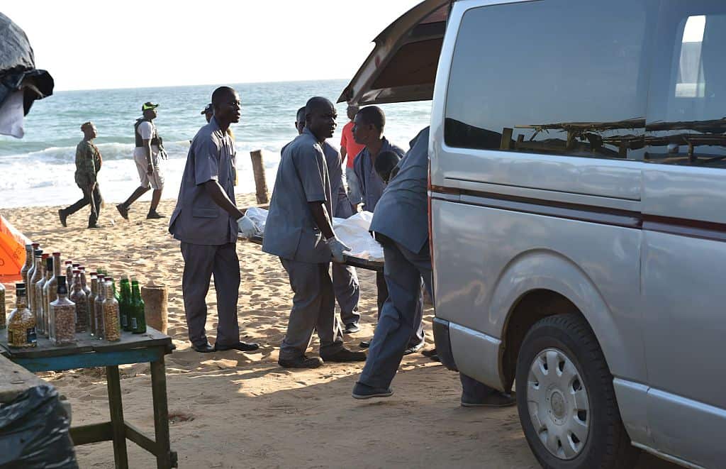 Employees load a body into a van after heavily-armed gunmen opened fire in the Ivory Coast resort town of Grand-Bassam