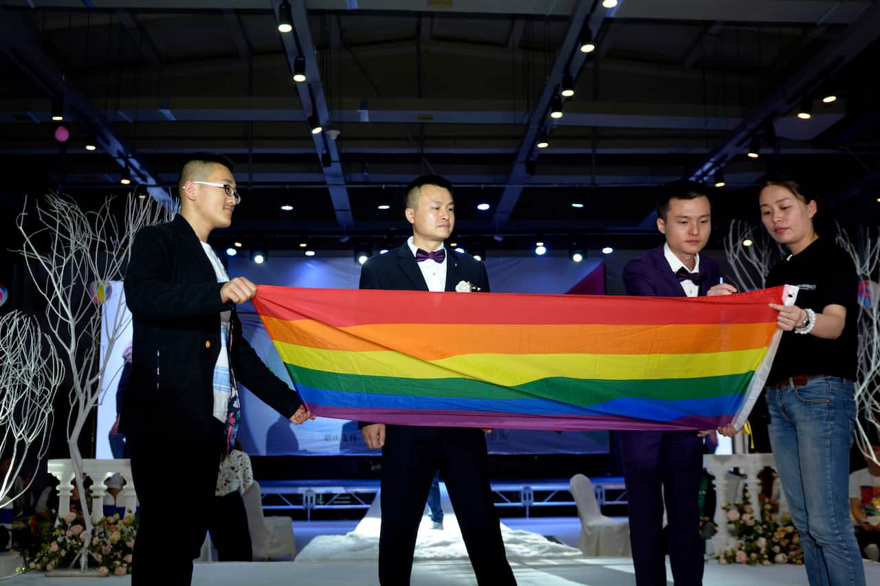 Hu Mingliang and his partner Sun Wenlin sign on a rainbow flag during their legally unrecognised wedding ceremony in central China. 