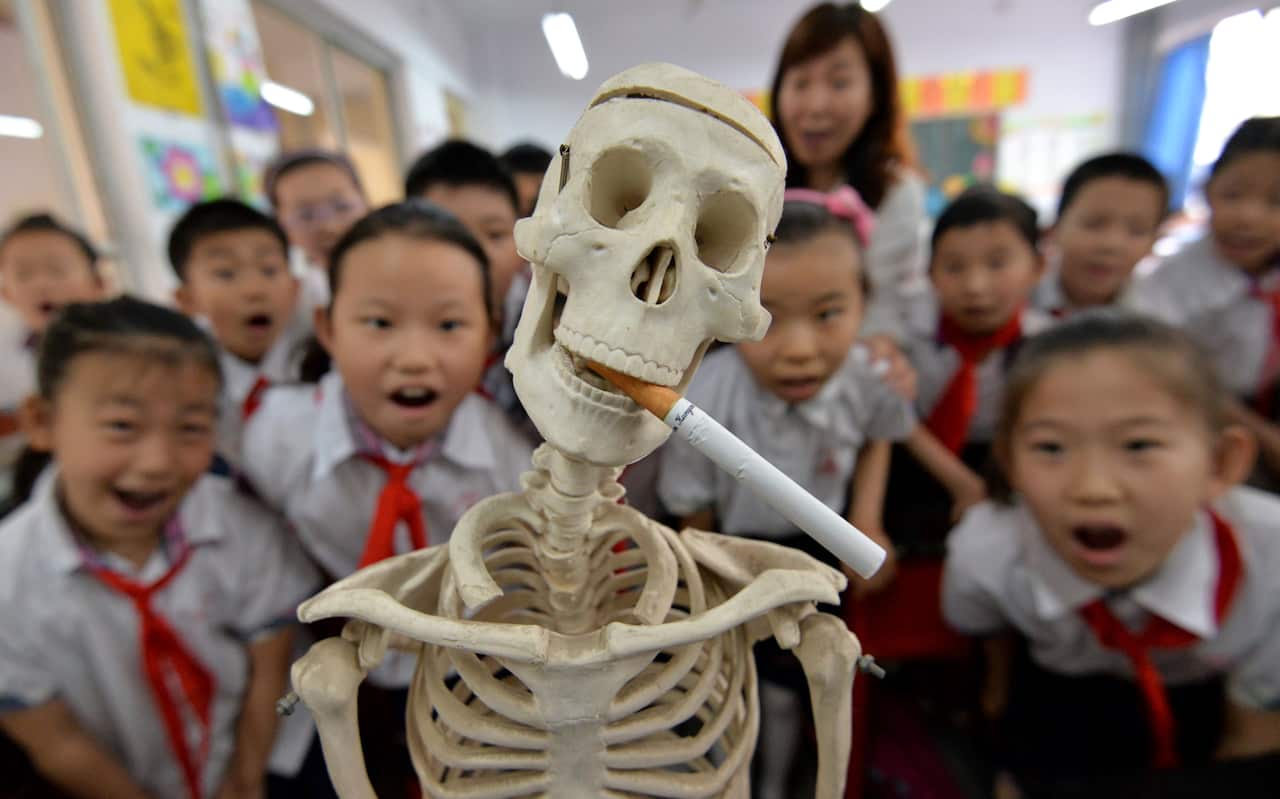 This photo taken on May 30, 2016 shows students wearing masks with no smoking signs to support World No Tobacco Day at a primary school in Handan, northern China's Hebei province. The slumping output of tobacco products in China has become one of the fact