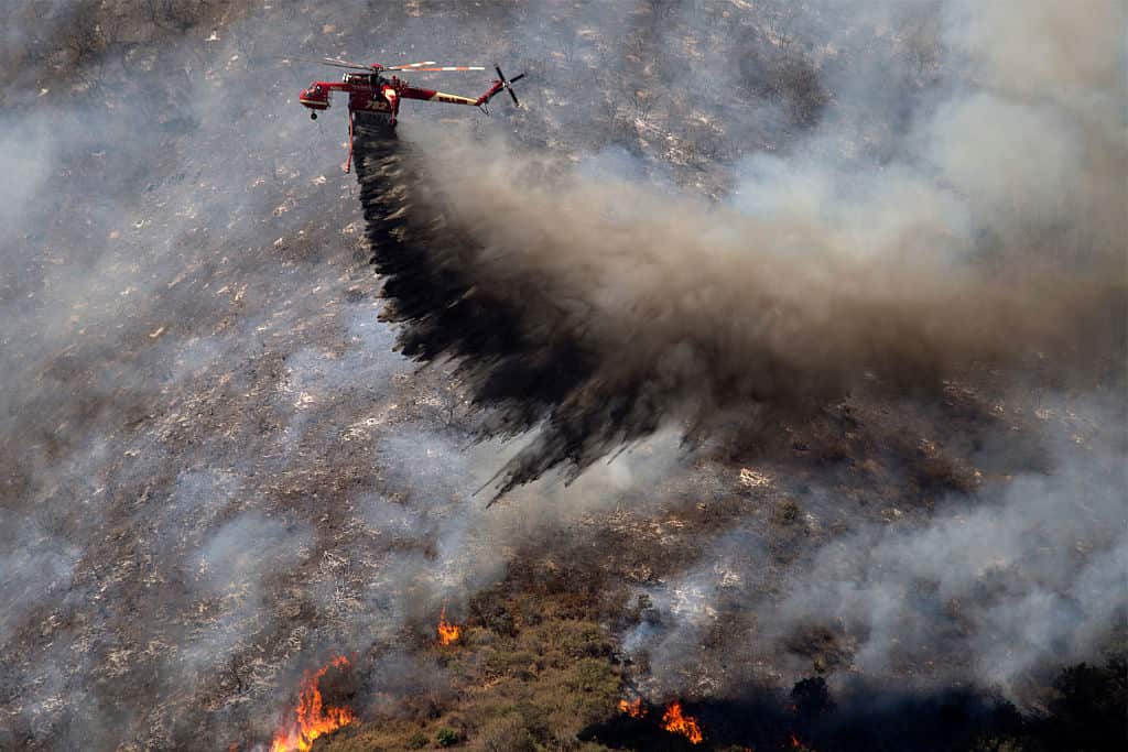 A firefighting helicopter makes a drop as firefighters try to gain control of the fire near Wrightwood, California. 
