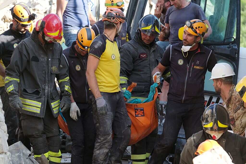 Rescuers carry the body of a victim in the Italian central village of Illica, near Accumoli on August 24, 2016 after a powerful earthquake rocked central Italy.