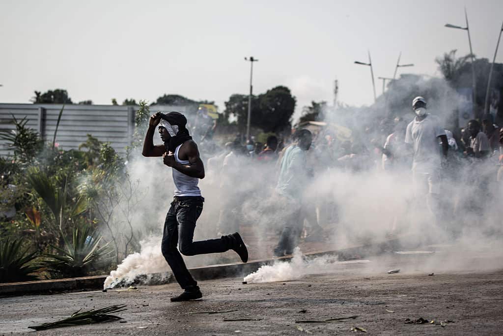A protester runs amid tear gas canisters during confrontations with the police in Libreville on August 31, 2016 