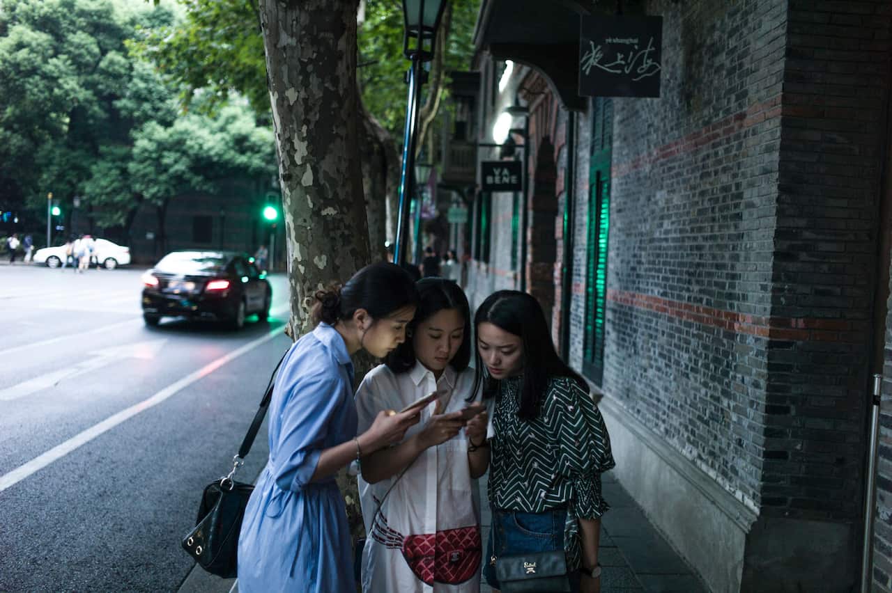 Women look at their smartphones in Xintiandi