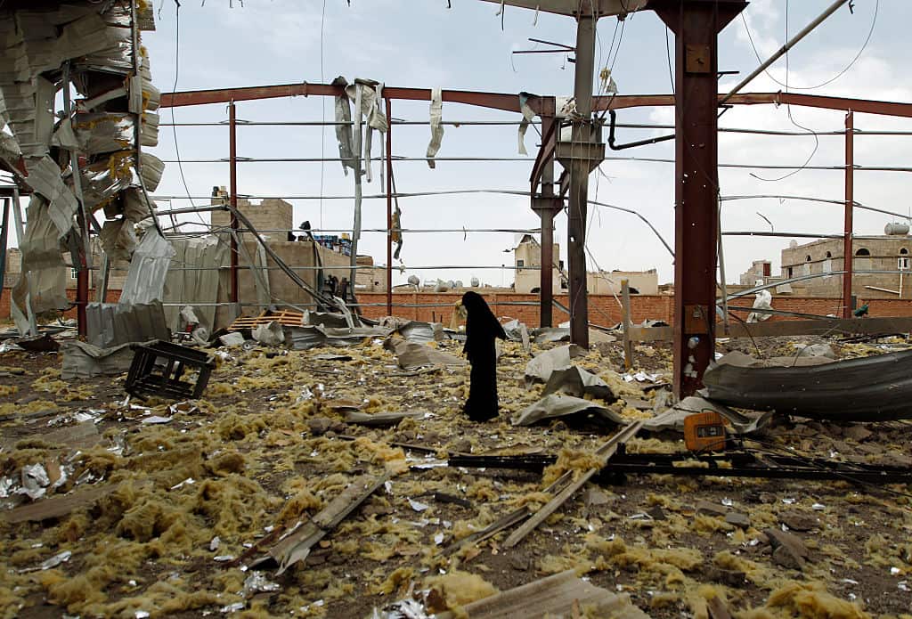 A Yemeni woman inspects the damage at a factory allegedly targeted by Saudi-led airstrikes in Sana'a, September 2016.