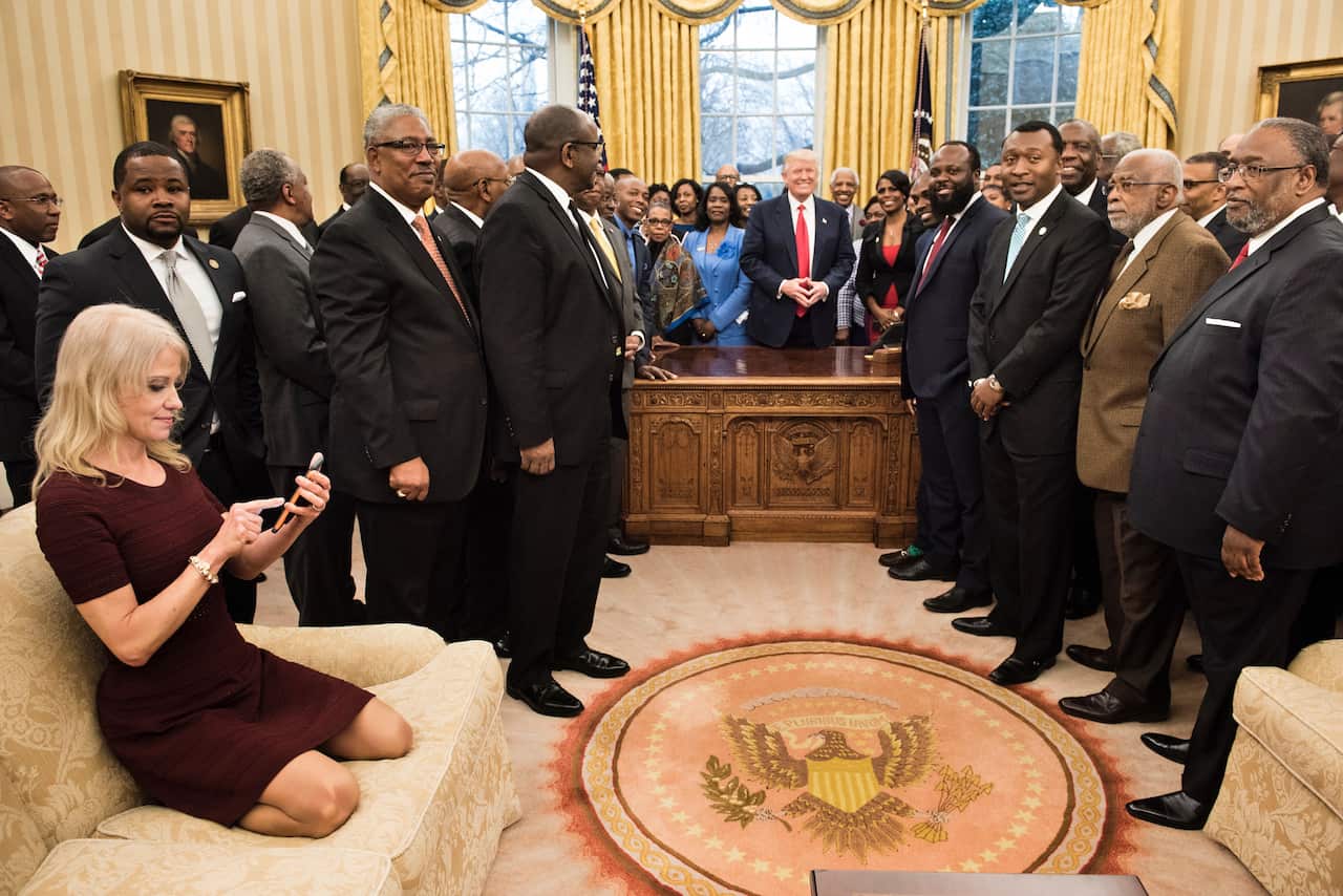 Counselor to the President Kellyanne Conway checks her phone after taking a photo of President Trump and leaders of historically black universities and colleges