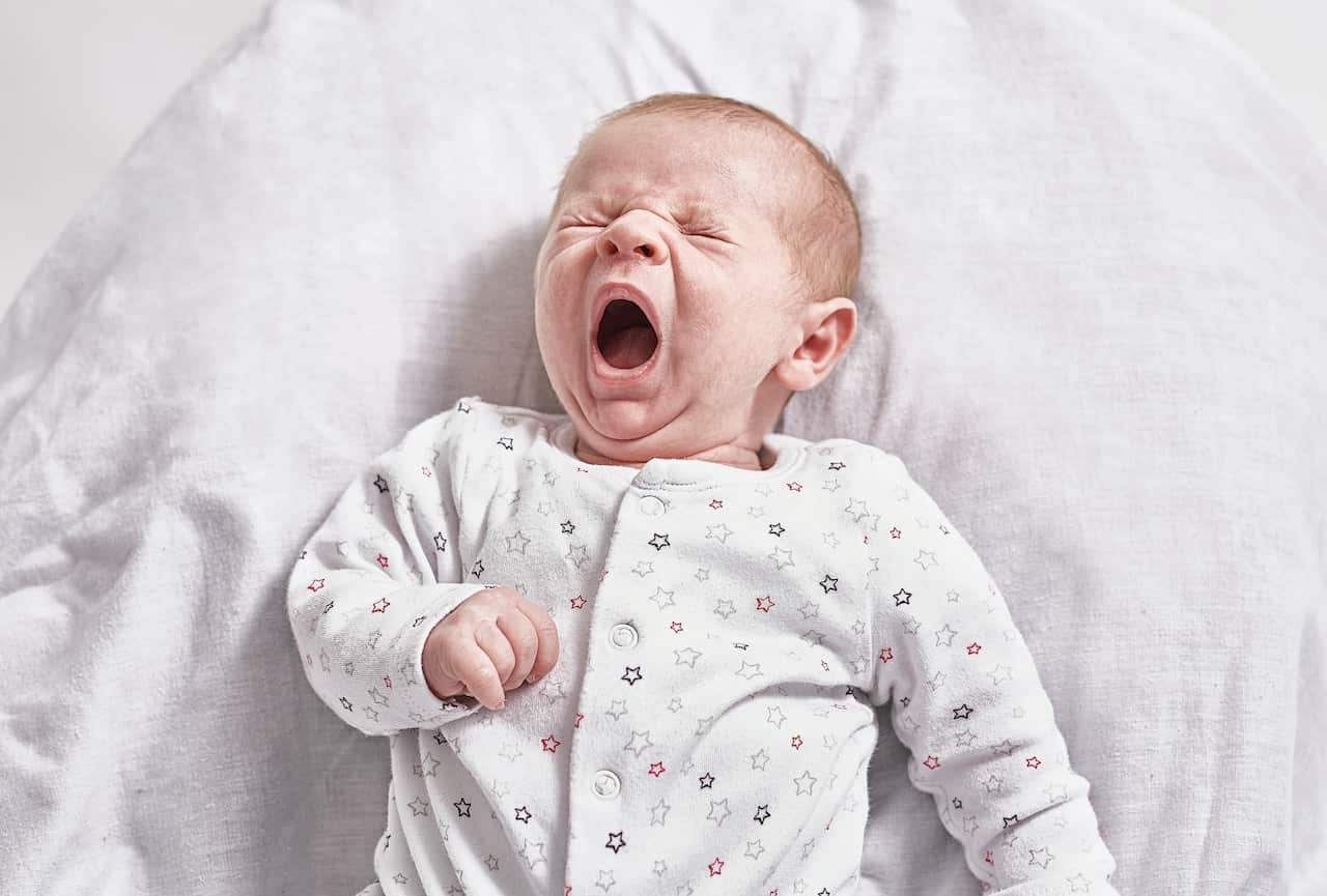 A portrait of a month old baby yawning.