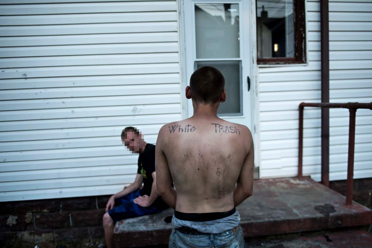 Two men wait while police search an abandoned house used by drug addicts, on April 19, 2017 in Huntington, West Virginia.