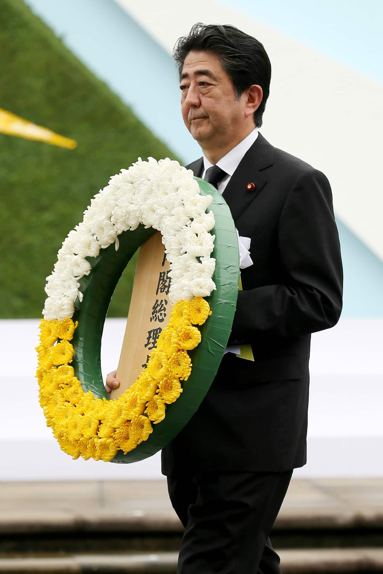 Japan's Prime Minister Shinzo Abe carries a wreath for atomic bomb victims during ceremony at Peace Memorial Park in Nagasaki, western Japan, on August 9, 2017.