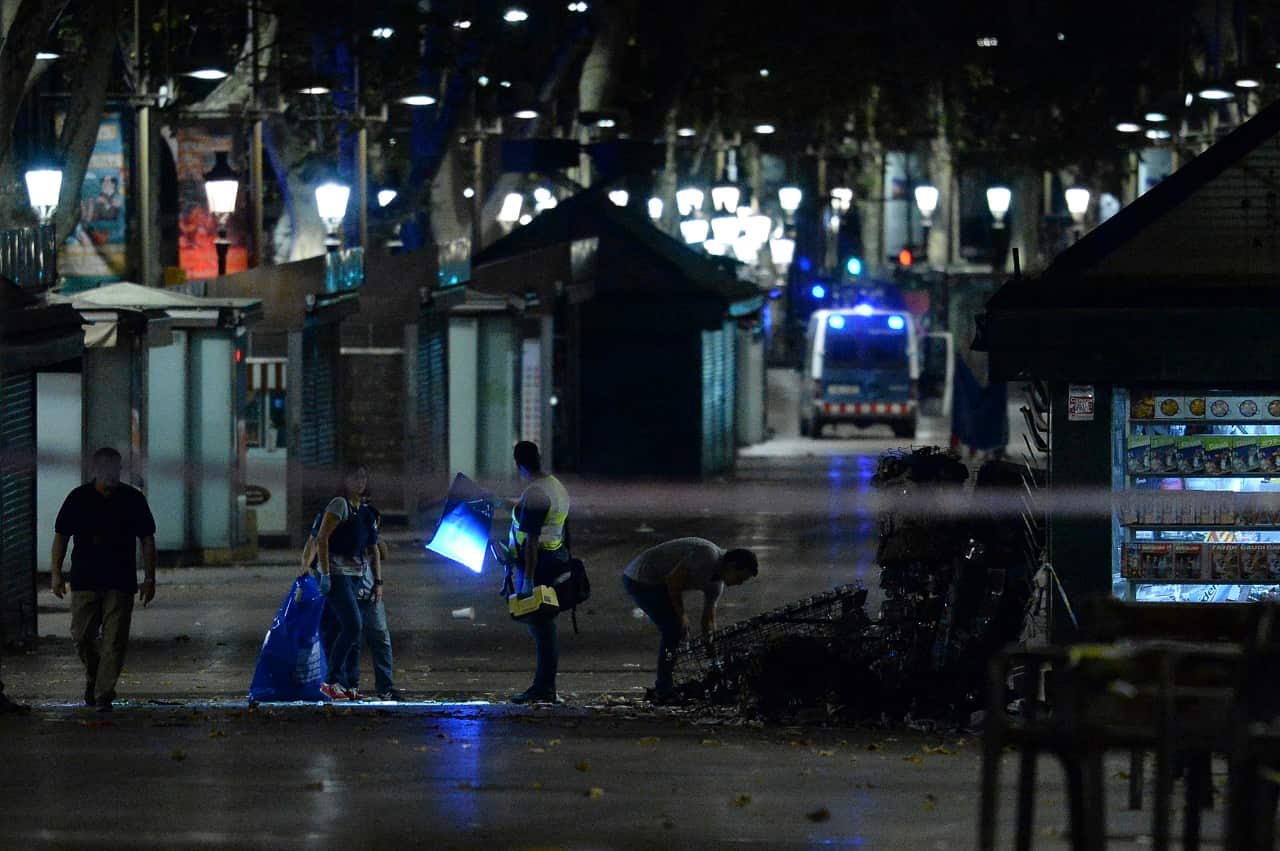 Policemen check the area after towing away the van which ploughed into the crowd in Barcelona.