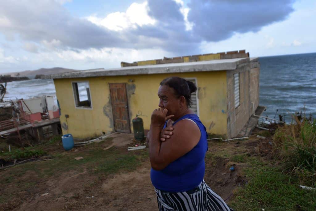 Maria Martinez stands next to her house which was damaged by Hurricane Maria in Puerto Rico