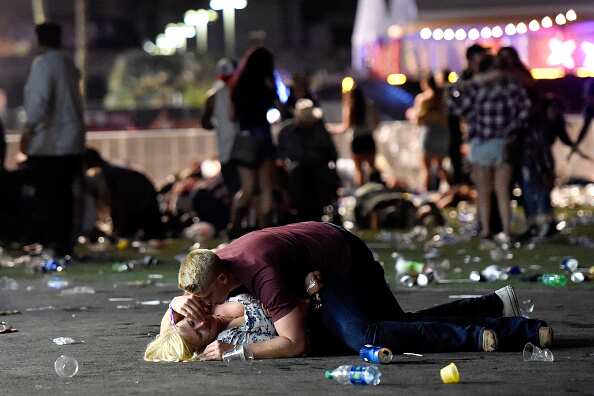 A man lays on top of a woman as others flee the Route 91 Harvest country music festival grounds after a active shooter was reported on October 1, 2017 in Las Vegas, Nevada. The photographer witnessed the man help the woman up and they walked away.