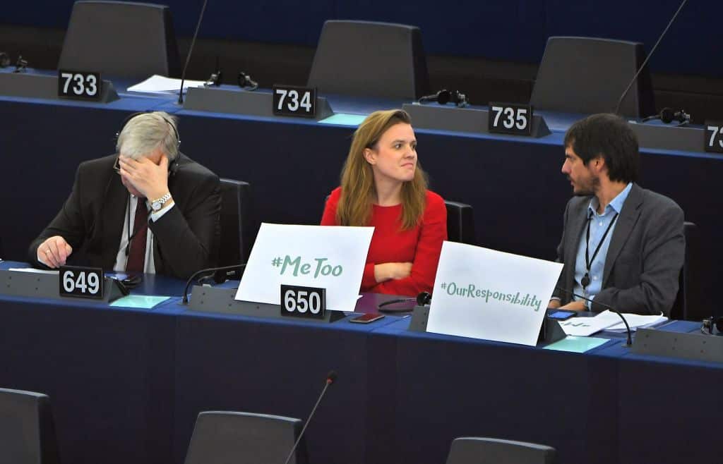 German MEP Terry Reintke (C) sits with a '#metoo' placard next to Lithuanian MEP Bronis Rope (L) and Austrian MEP Michel Reimon, during a debate in the EU.