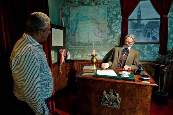A Palestinian looks at a scene depicting Arthur Balfour signing a declaration at street artist Banksy's Walled Off hotel.