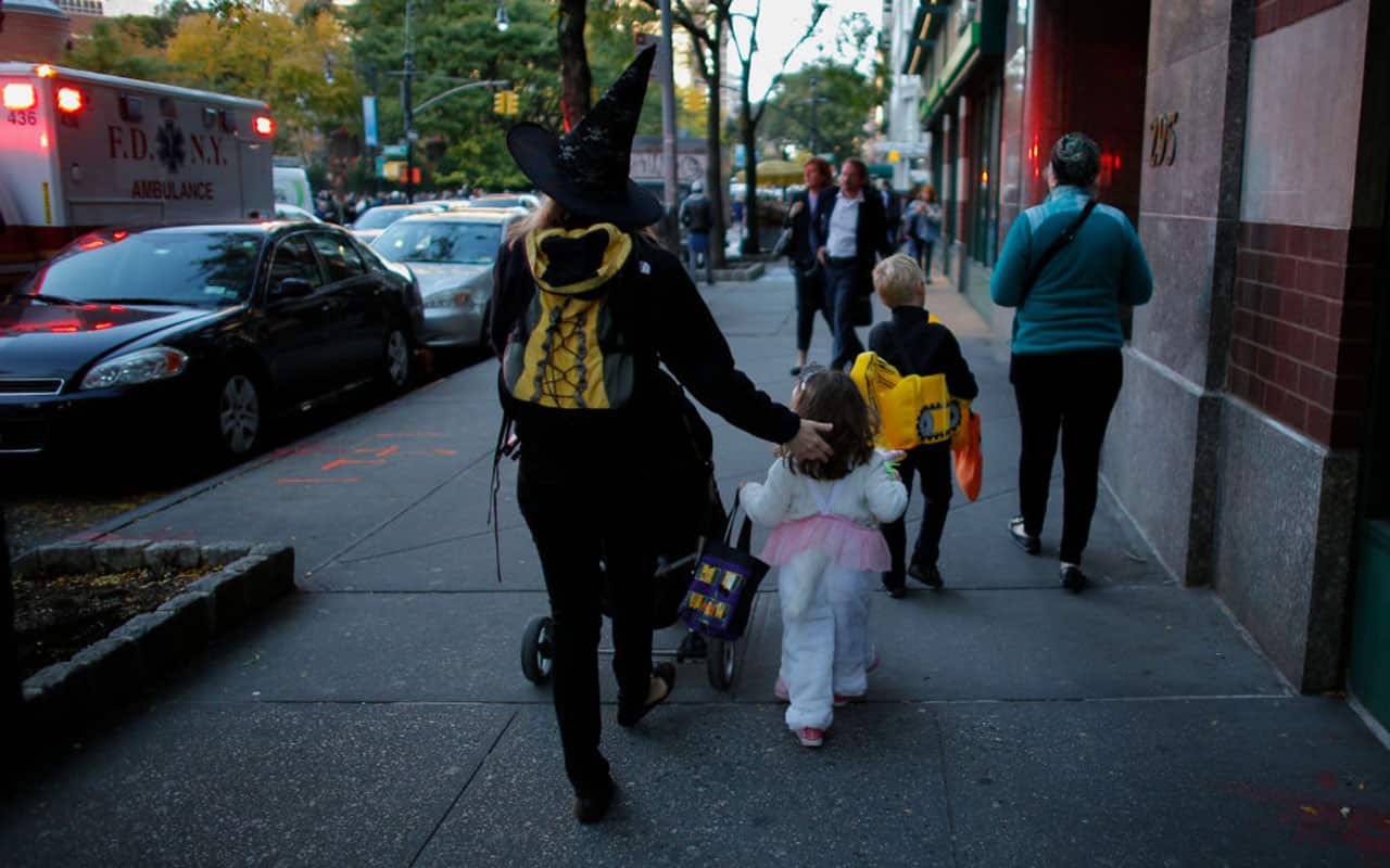 Kids in Halloween costumes cross the street near the scene where a man driving a rental truck struck and killed eight people.