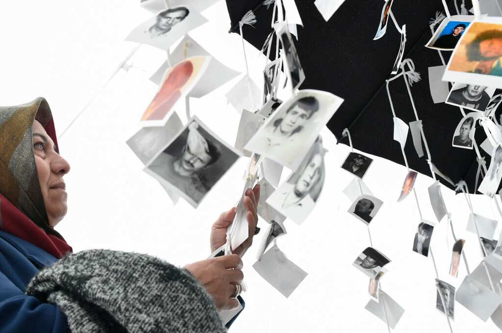 A woman looks at pictures of victims inside the memorial of victims, in front of the International Criminal Tribunal for the former Yugoslavia (ICTY) in The Hague, on November 22, 2017, prior to the verdict in the genocide trial of former Bosnian Serbian.