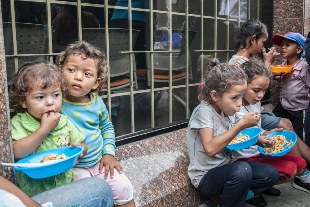 Venezuelan children heat food distributed from volunteers.