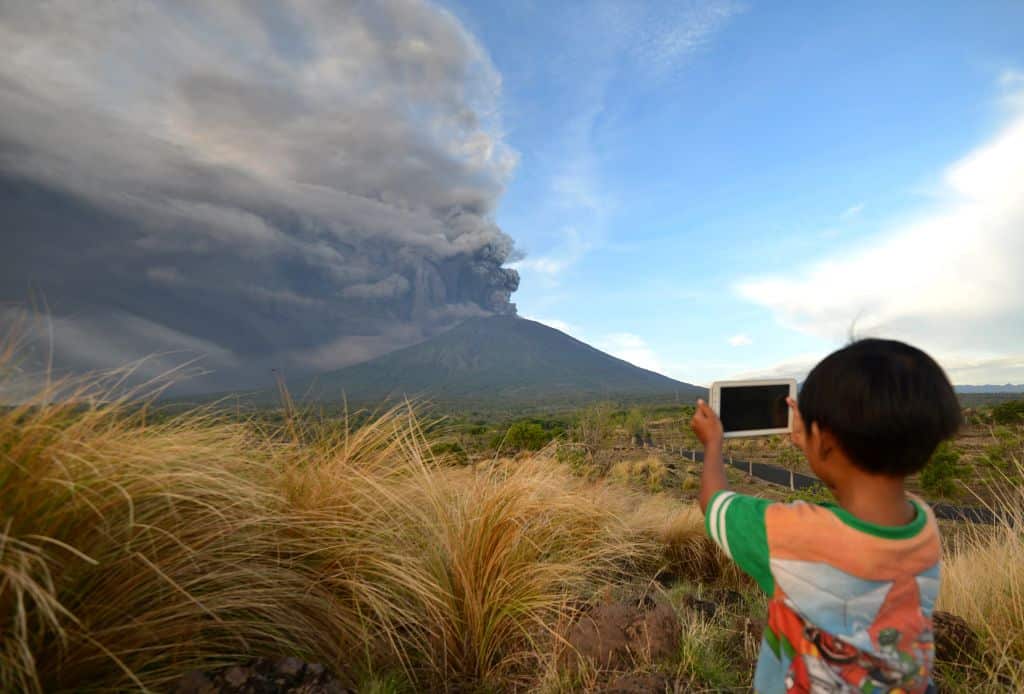 A boy takes pictures during Mount Agung's eruption seen from Kubu sub-district in Karangasem Regency on Indonesia's resort island of Bali on November 26, 2017.