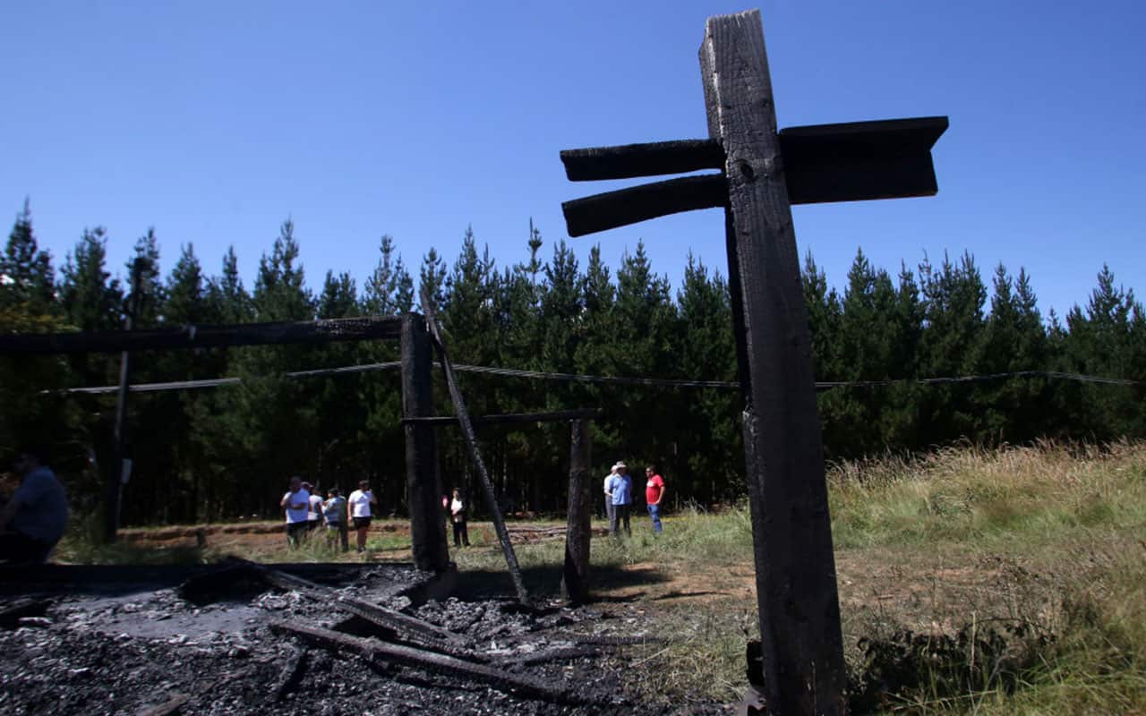 People stand amid the rubble of a burnt out chapel, which was attacked with an incendiary device in Cunco, Araucania region, Chile on January 16, 2018. 