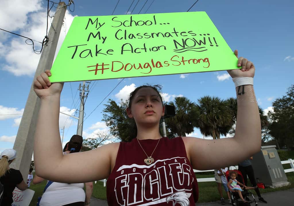 Student Angelia Lazo holds up a sign while standing near the Marjory Stoneman Douglas High School where 17 people were killed on February 14, on February 18