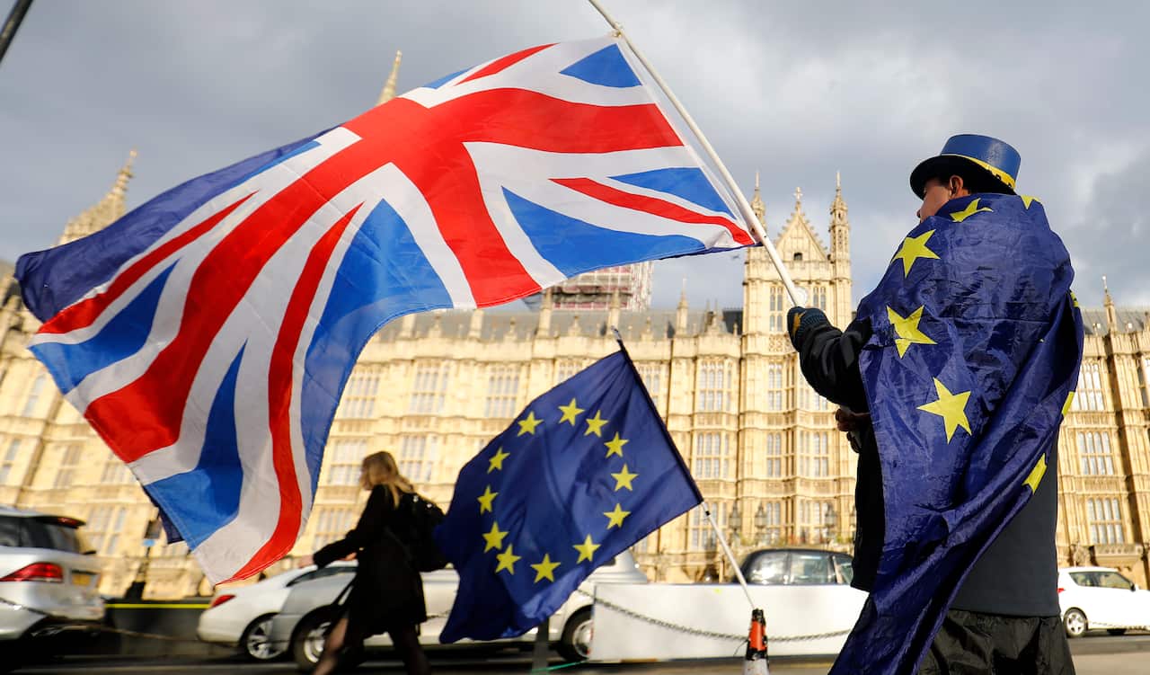 An anti-Brexit demonstrator waves a Union flag alongside a European Union flag outside the Houses of Parliament in London.