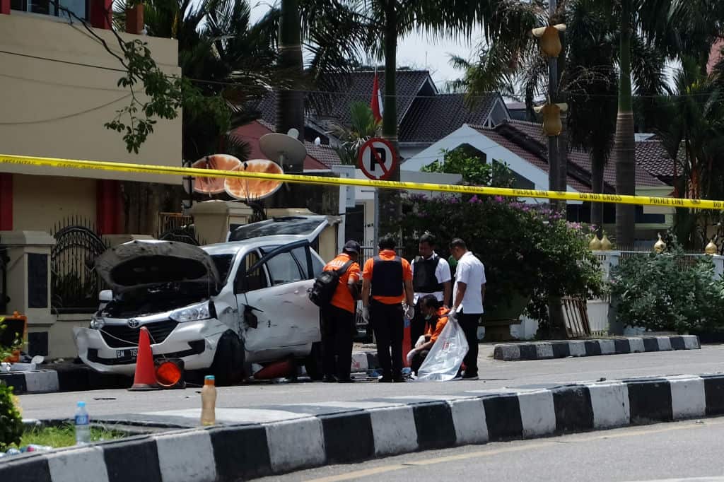 Indonesian policemen examine a car used by attackers outside the police headquarter in Pekanbaru, Riau.