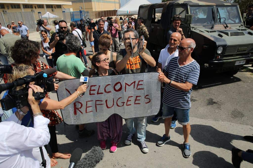 People hold a  placard reading "Welcome refugees" as they protest against the visit of Italy's new hardline interior minister .