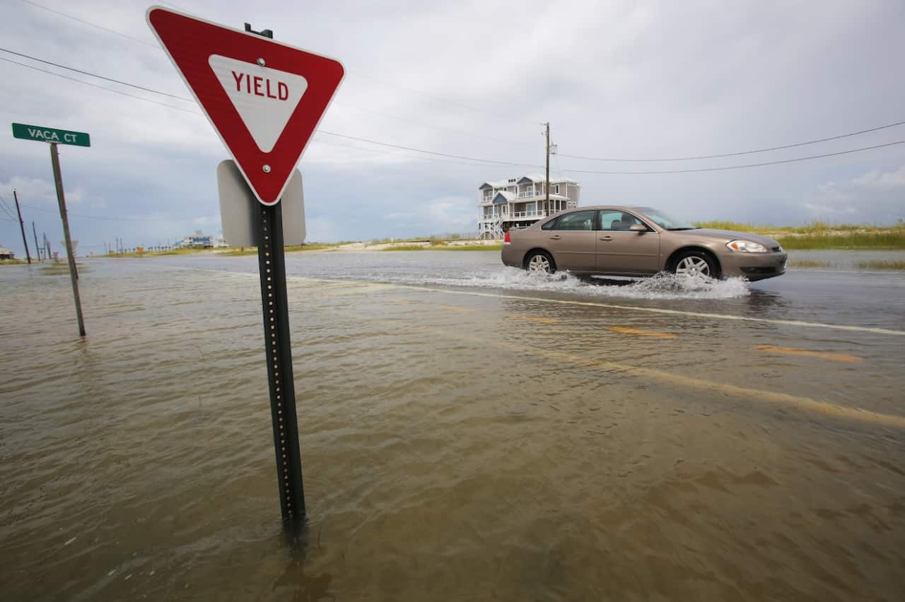 A car drives through a road as it slowly begins to flood as Tropical Storm Gordon approaches on Tuesday, Sept. 4, 2018