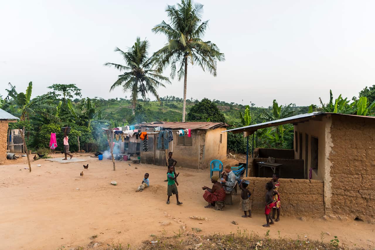 Sampson Amekoe, a plantain farmer with albinism, sits with his mother and children in a remote village in the Koforidua region of Ghana.