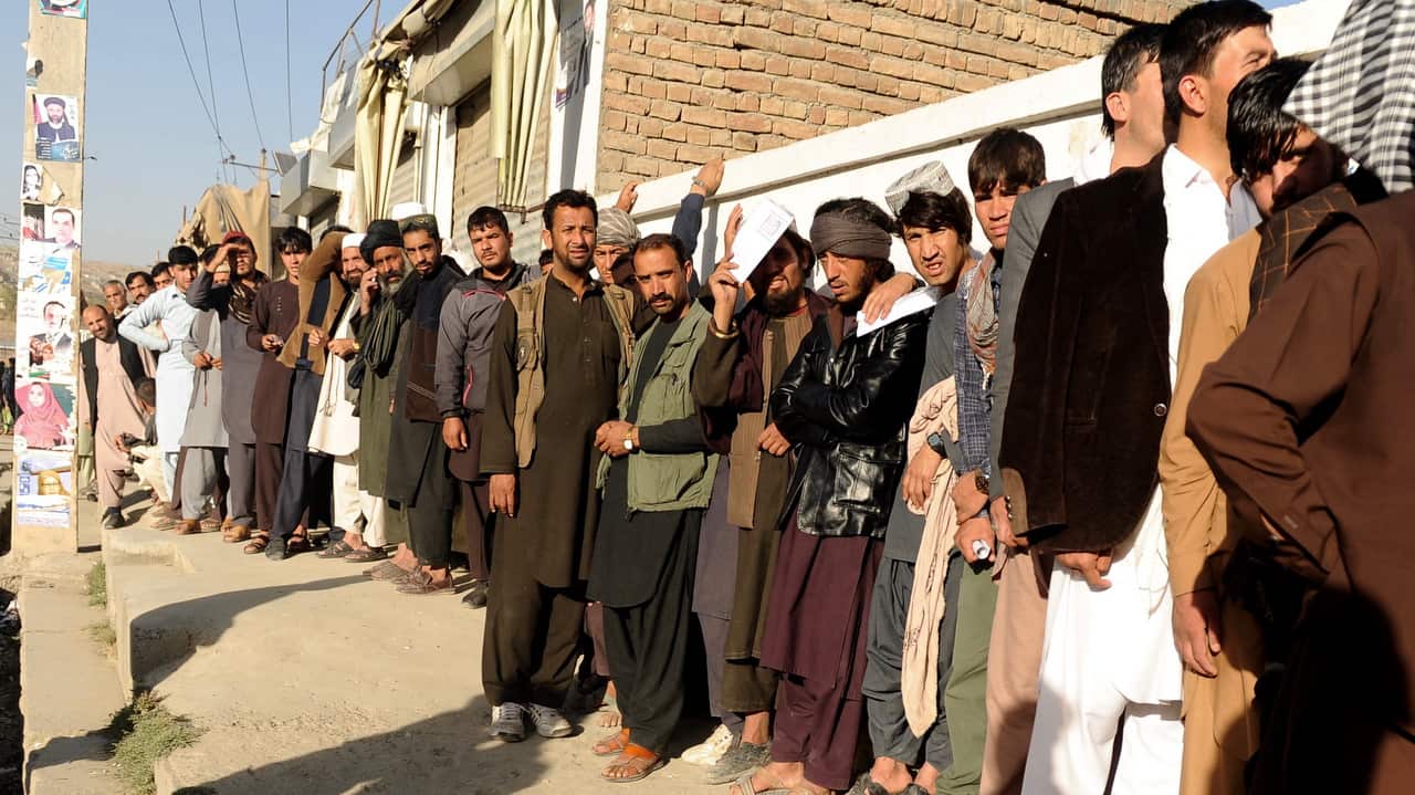 Afghan men stand line to cast their votes outside a polling center in Kabul, Afghanistan.