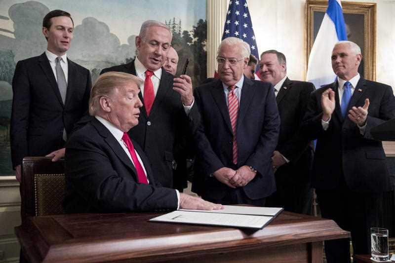Prime Minister of Israel Benjamin Netanyahu hands a pen to US President Donald J Trump as he signs the order.