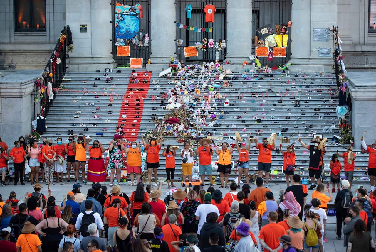 First Nations people raise their hands during a vigil for the 215 children whose remains were found buried at the former Kamloops Indian Residential School.