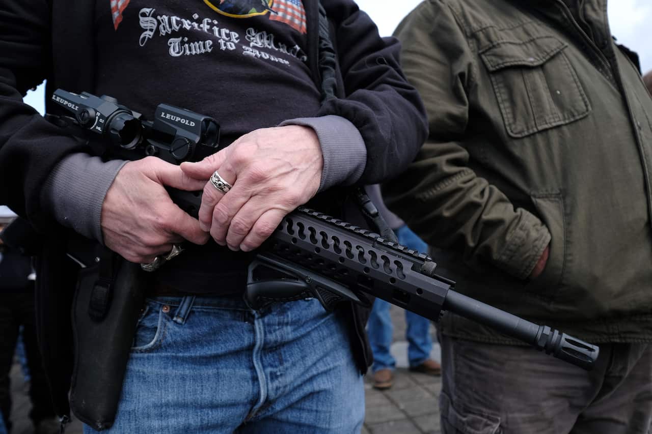 A man holds an AR-15 rifle, a popular choice among both gun hobbyists in the US and mass shooters.  