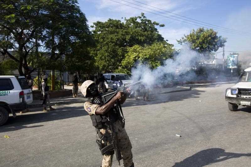 Police disperse the crowd with tear gas, away from the site where a car that careened out of control hit a group of persons in Port-au-Prince.