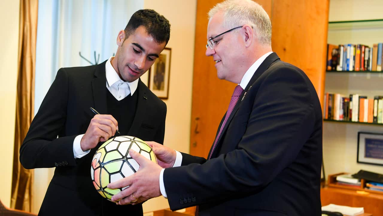 Australian Prime Minister Scott Morrison (right) gets footballer and refugee Hakeem al-Araibi to sign a ball during a meeting at Parliament House.