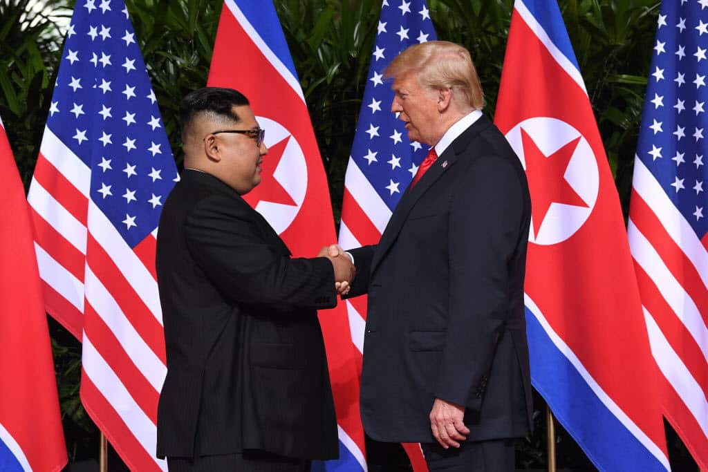 Kim Jong-un (L) shakes hands with US President Donald Trump (R) at the start of their historic US-North Korea summit.