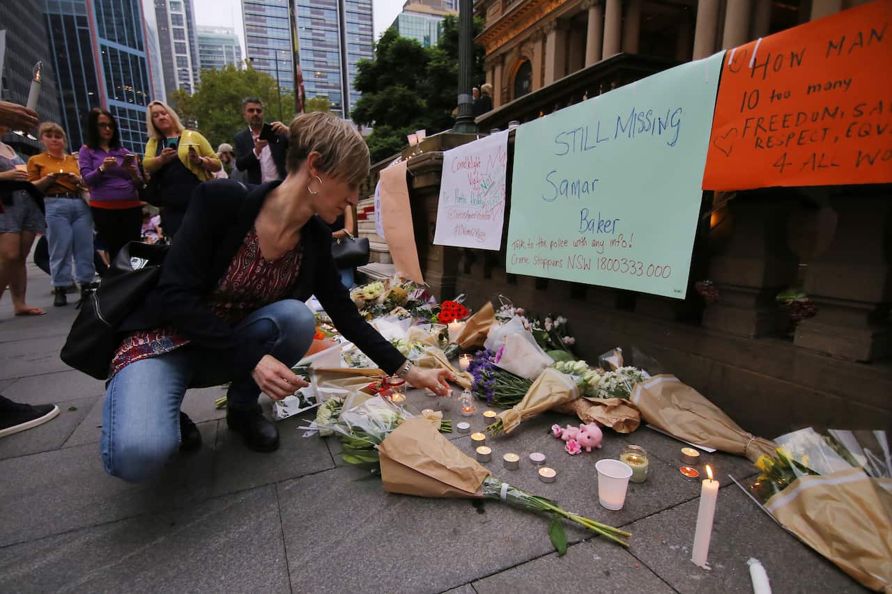 Director of the Women's Domestic Violence Court Advocacy Services NSW Hayley Foster places flowers during a candlelight vigil for a victim of domestic violence.