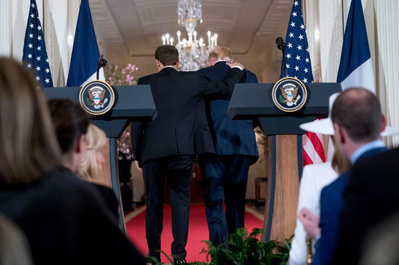 French President Emmanuel Macron puts his arm around President Donald Trump as they leave a news conference in the East Room of the White House