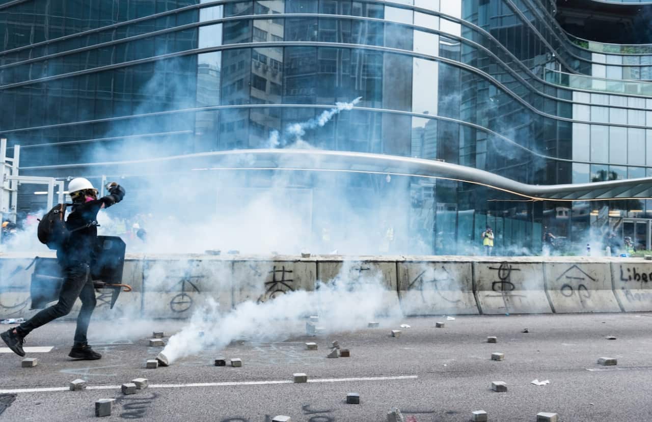 A protester throws a canisters of tear gas back towards the police during the demonstration. 
