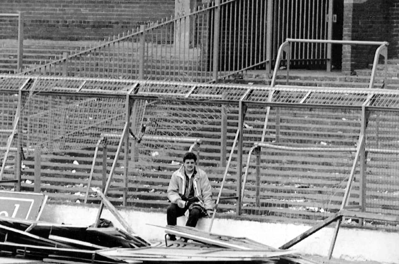 A file photo of a lone supporter siting by the damaged fencing at Hillsborough Stadium, in Sheffield, April 15, 1989 (AAP)