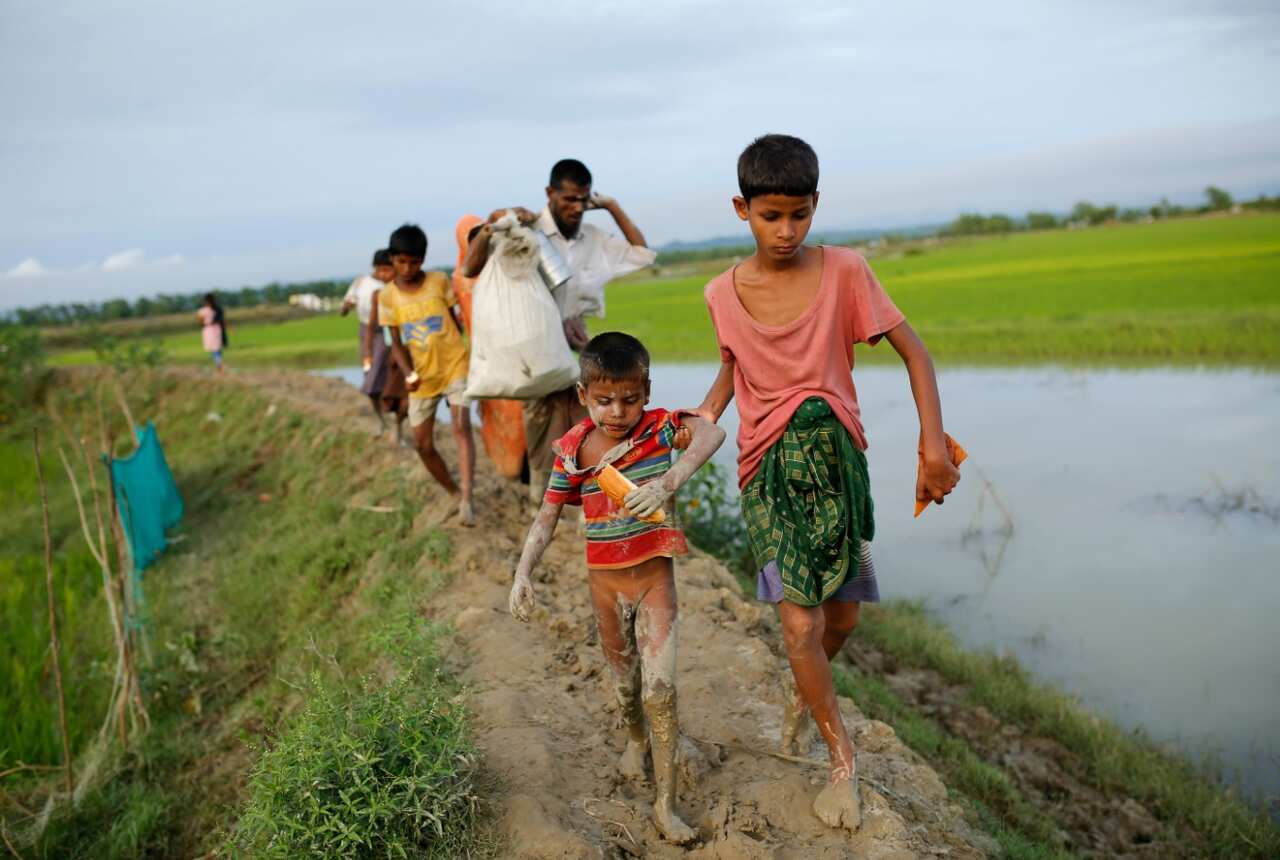 Rohingya refugees walk in a muddy road as they enter Bangladesh border in Teknaf, Bangladesh, 10 September 2017 (AAP)