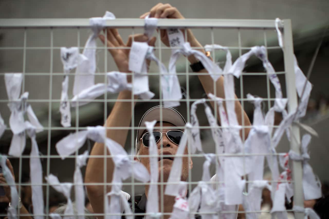 An elderly man ties ribbons with messages of support for young protesters during a rally in Hong Kong.