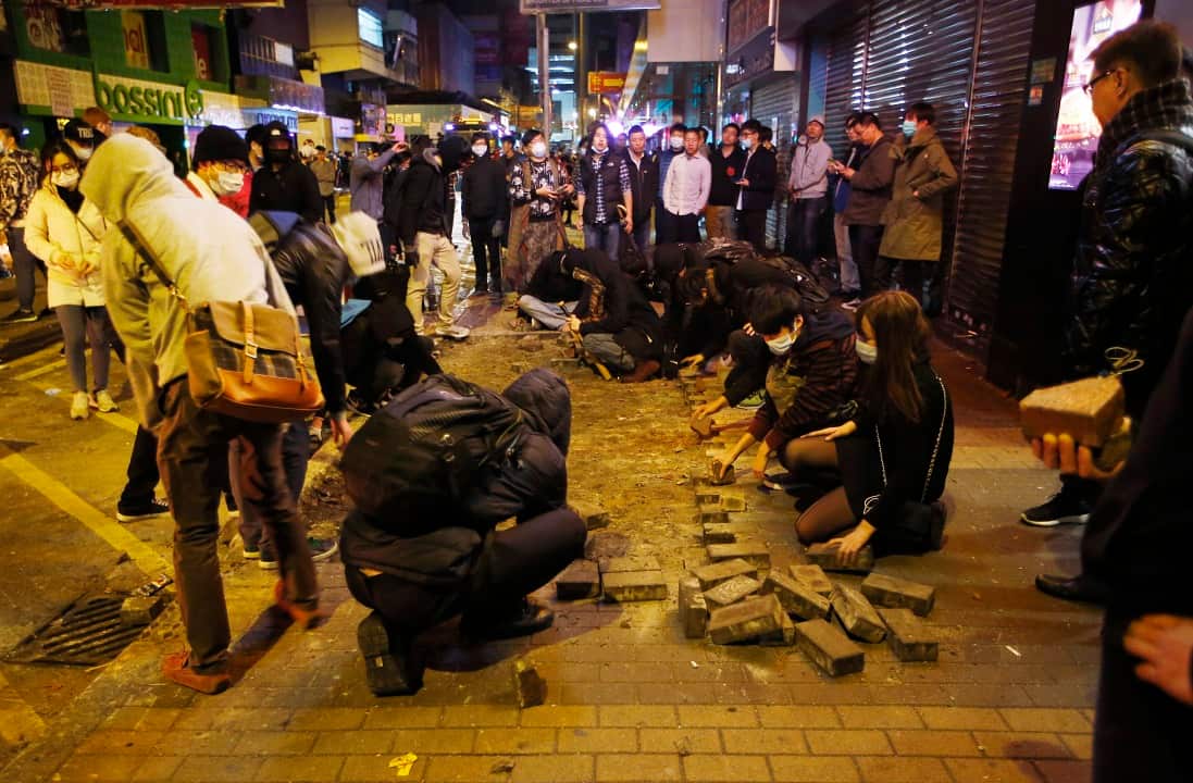 Protesters collect bricks from a pathway during clashes with
