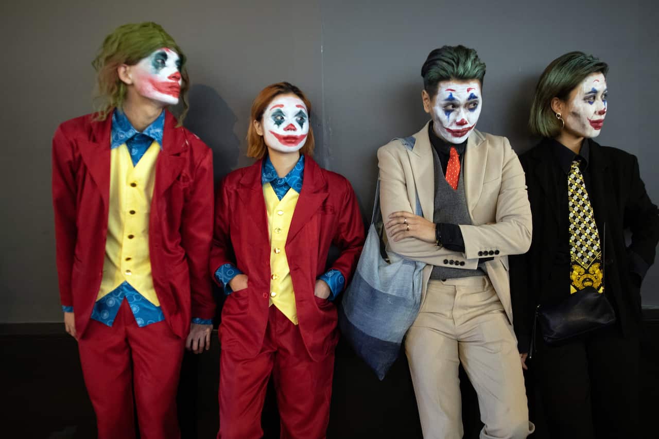 A group of revelers dressed as Jokers watch police disperse protesters. Hong Kong has officially enacted laws banning masks and face paint. 