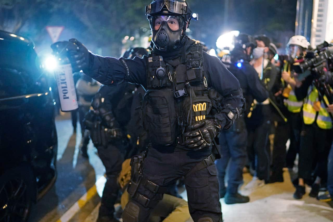 A riot police gestures, to a crowd to clear the area during a rally on Christmas Eve in Hong Kong.