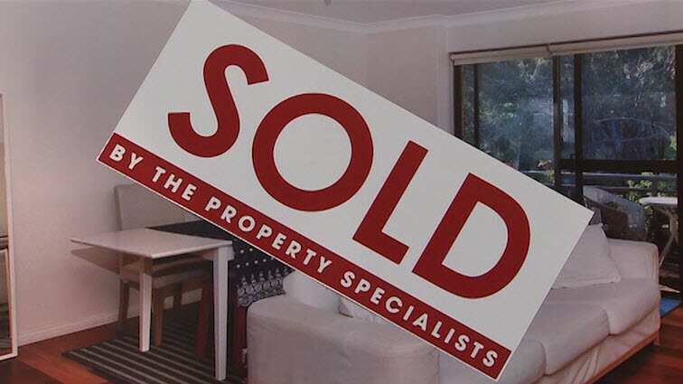 A sticker reading SOLD across a picture of a lounge room