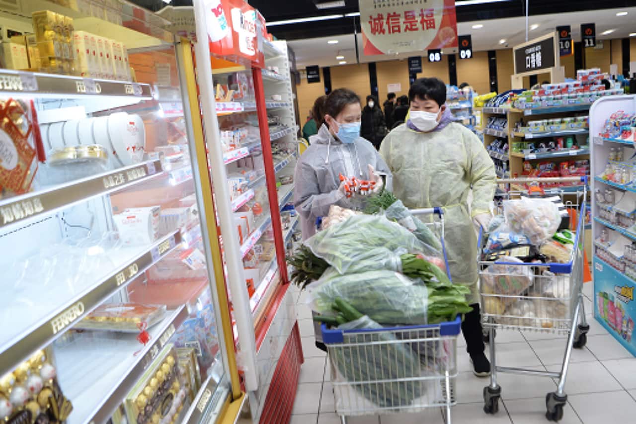 Masked shoppers wearing plastic coats shop in a supermarket in Wuhan, the epicenter of the coronavirus outbreak.