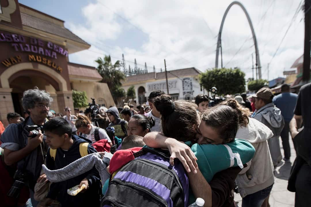 Central Americans who travel with a caravan of migrants embrace before crossing the border and request asylum in the United States.