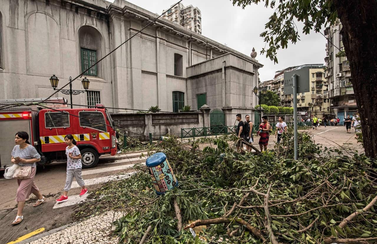 Pedestrians pass by a fallen tree after the passage of Typhoon Hato in Macau, China, 23 August 2017. 