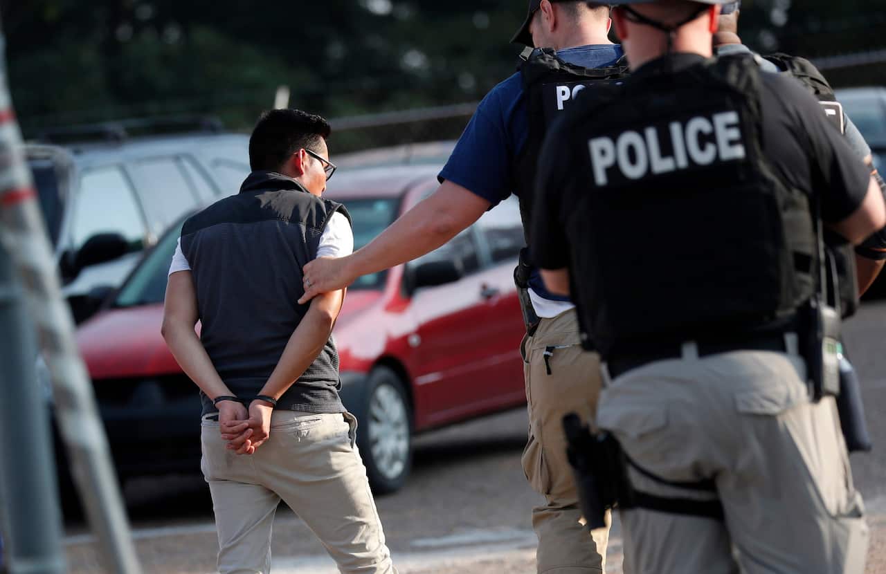 A man is taken into custody during an immigration raid at a Koch Foods plant in Morton on Wednesday. 